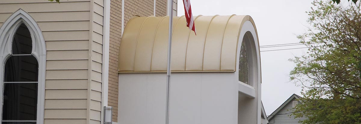 Church entry with a custom standing-seam metal barrel canopy fabricated and installed by Peterson Roofing