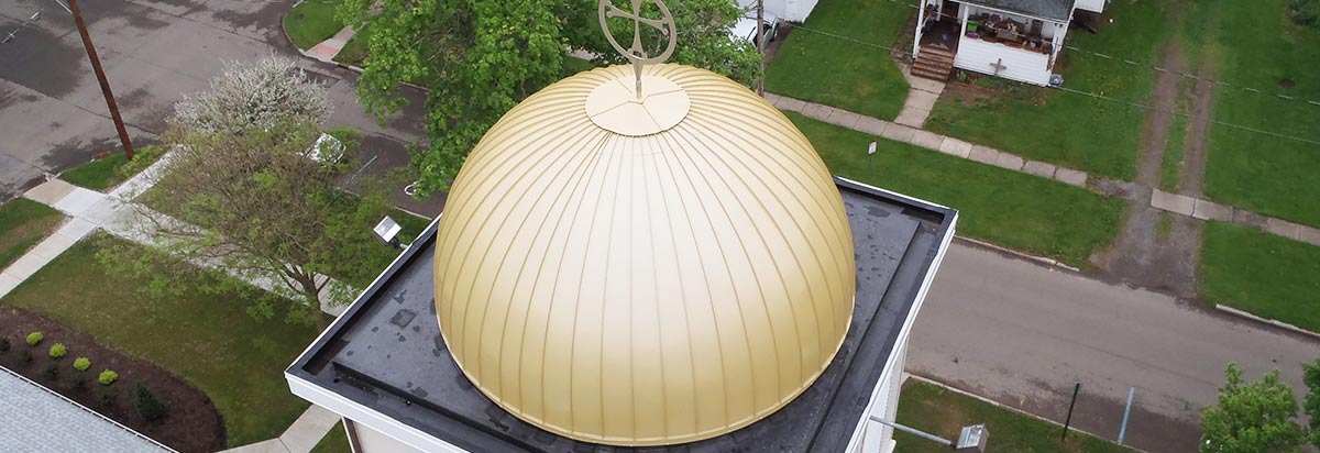 Golden domed church roof with a cross over a low-slope membrane deck
